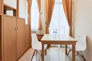 A modern kitchen with a wooden cabinet, a white table, and two white chairs. - Airy And Cozy Combined Loft Unit 2Br At Apartment Apple 1 Condovilla (Jakarta)