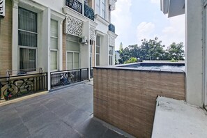A building with large windows, a balcony with a railing, and a view of trees and a building in the background. - Airy And Cozy Combined Loft Unit 2Br At Apartment Apple 1 Condovilla (Jakarta)