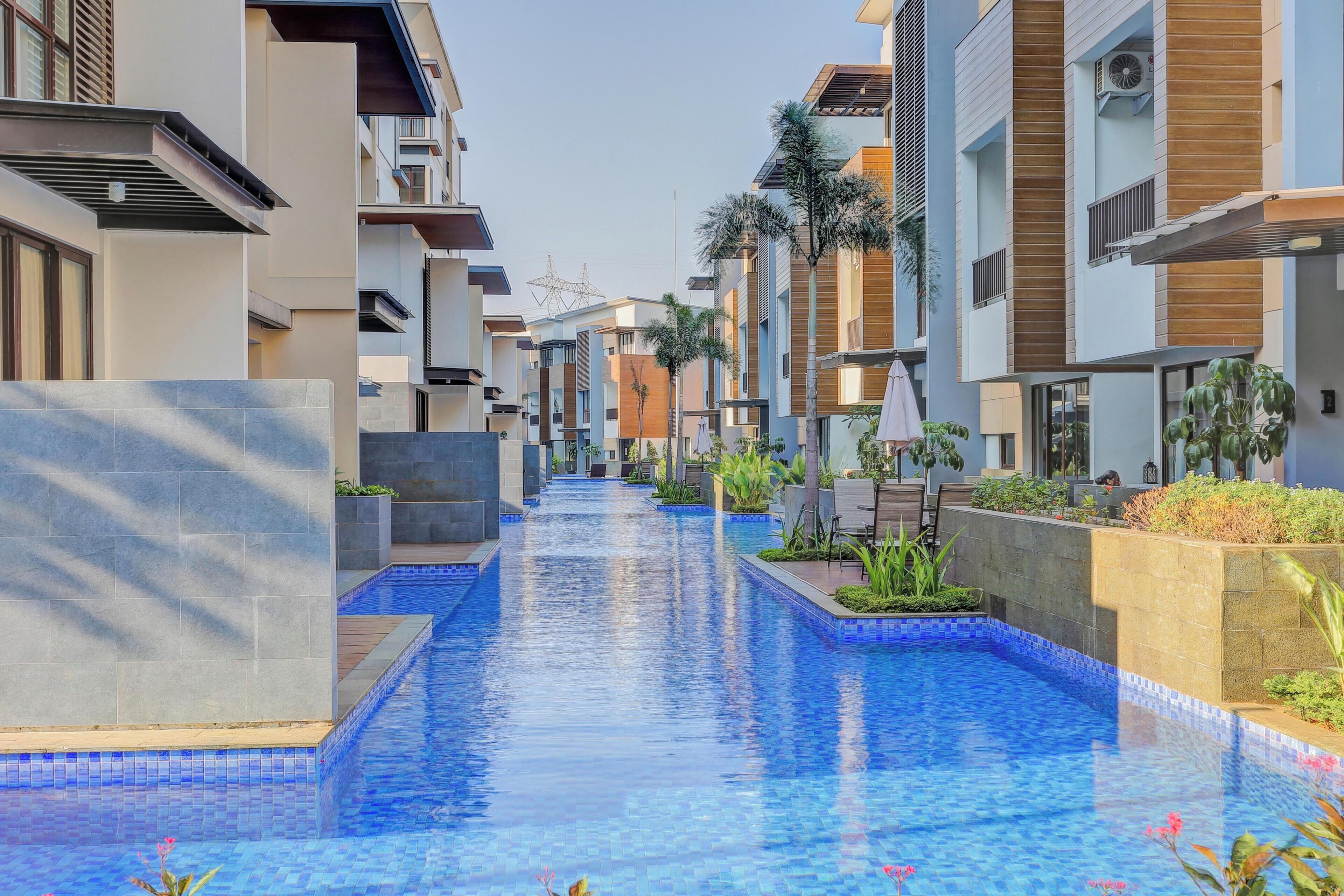 Un hotel moderno con piscina central, balcones y cielo despejado.