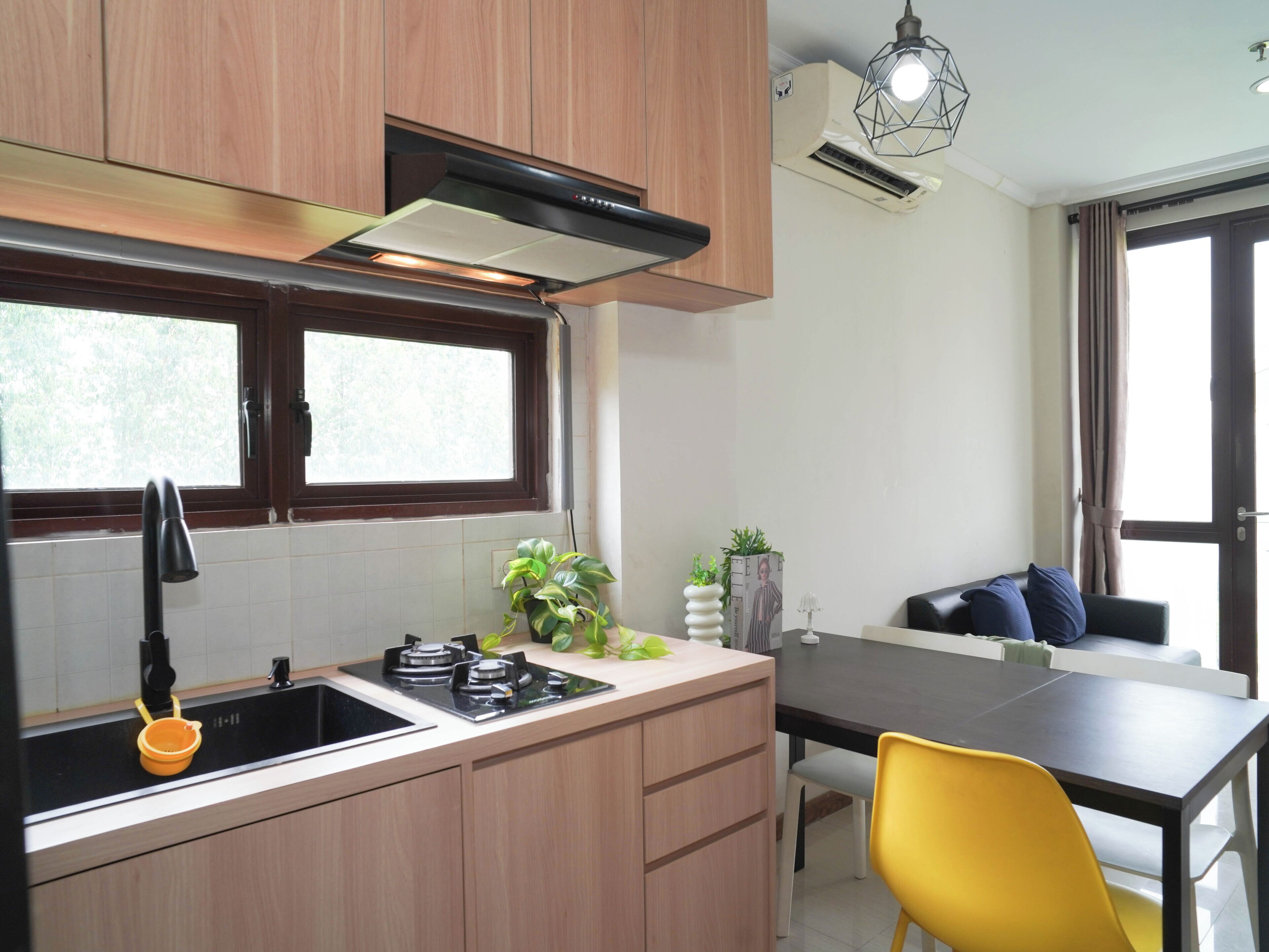 A modern kitchen with wooden cabinets, a black sink, and a dining area with a table and chairs.
