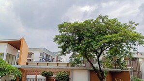 Ein modernes Gebäude mit einem Schild mit der Aufschrift 'ASATTI' und einem Baum im Vordergrund.