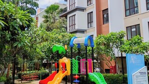 Ein Spielplatz mit Rutschen und Klettergerüsten, umgeben von Grünflächen und Wohnhäusern.