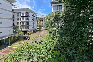 A residential building with multiple floors, balconies, and a parking area. - Cozy Stay 3Br At Asatti Apartment (Pagedangan)