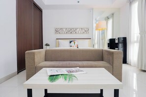 Ein modernes Hotelzimmer mit Schlafsofa, Nachttisch mit Zeitschrift und Pflanze, Wanddeko und Wasserspender.