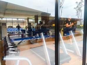 A gym with exercise equipment, a treadmill, and a mirrored wall. - Clean And Relaxing Studio Room At Apartment Azalea Suites (Cikarang)