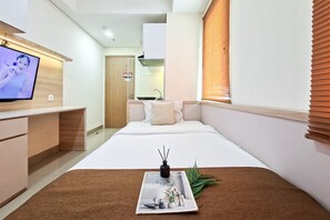 Ein modernes Hotelzimmer mit Bett, Fernseher, einer Zeitschrift auf dem Bett und einer Pflanze.