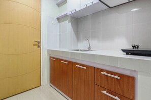 Cozinha com azulejos brancos, uma porta de madeira e bancada com pia.