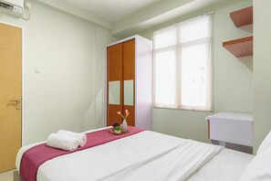 A hotel room with a bed, a wardrobe, a window with blinds, a bedside table, and a wall-mounted air conditioner. - Convenient 2Br For 4 Pax At Bale Hinggil Apartment (Surabaya)