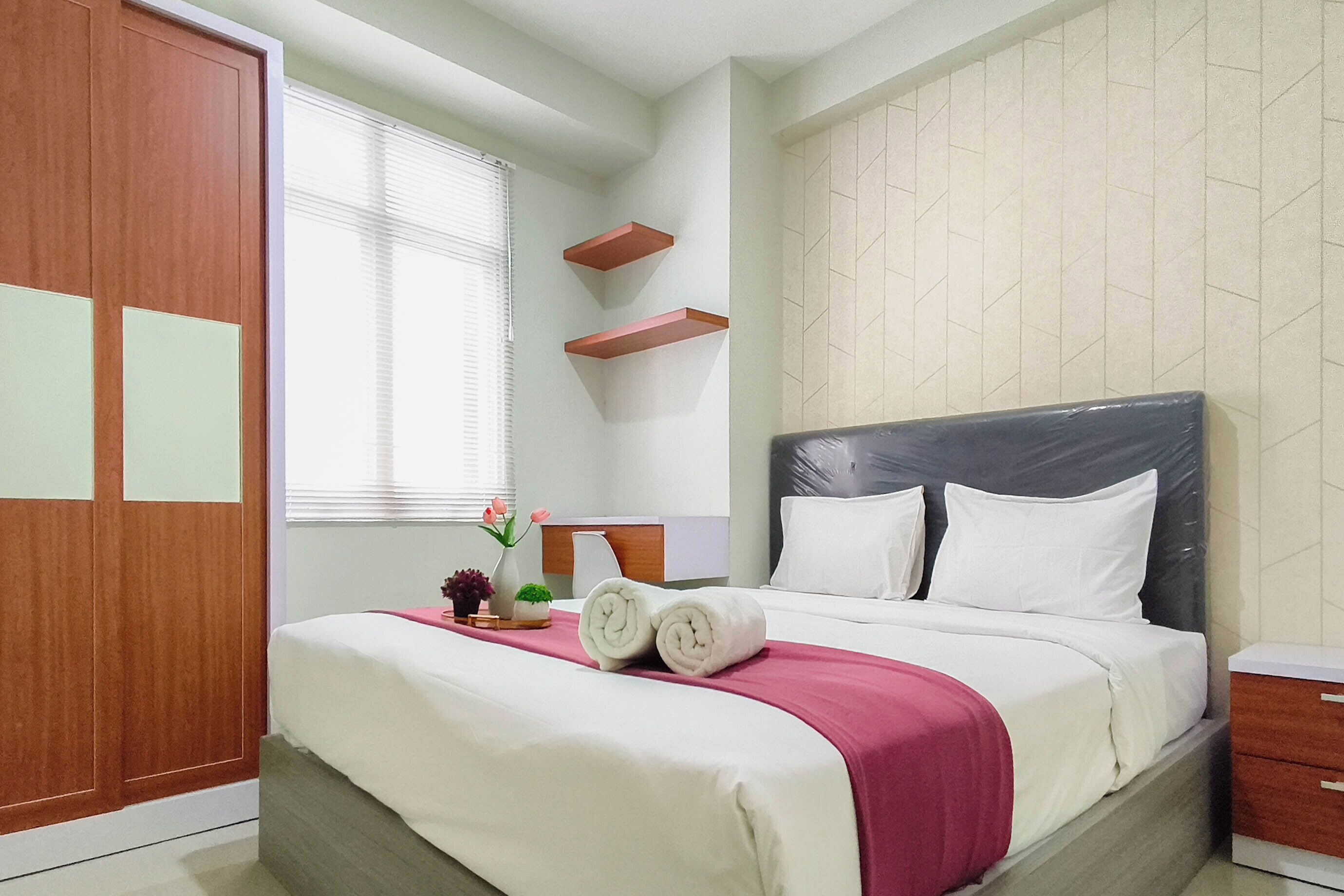 Une chambre d’hôtel avec un lit, une armoire en bois, une fenêtre avec des stores et un mur orné d’un motif géométrique.