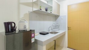 Uma cozinha compacta com geladeira, chaleira, pia e uma porta.