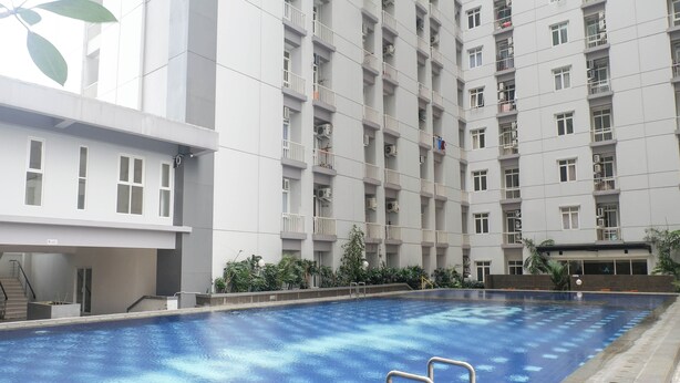 Piscina com superfície de água azul cristalina, rodeada por um edifício moderno com várias varandas e janelas.