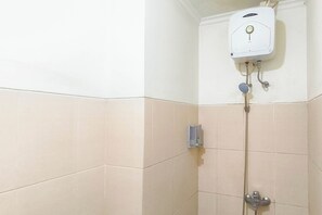 A bathroom with a white tiled wall, a white water heater, and a shower fixture. - Studio Minimalist And Comfortable At Bale Hinggil Apartment (Surabaya)