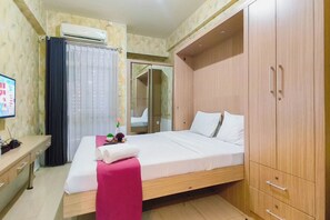 A hotel room with a bed, a desk, a wardrobe, and a mirror. - Studio Minimalist And Comfortable At Bale Hinggil Apartment (Surabaya)