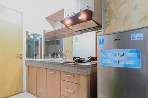 A kitchen with wooden cabinets, a stainless steel refrigerator, a gas stove, and a built-in oven. - Studio Minimalist And Comfortable At Bale Hinggil Apartment (Surabaya)