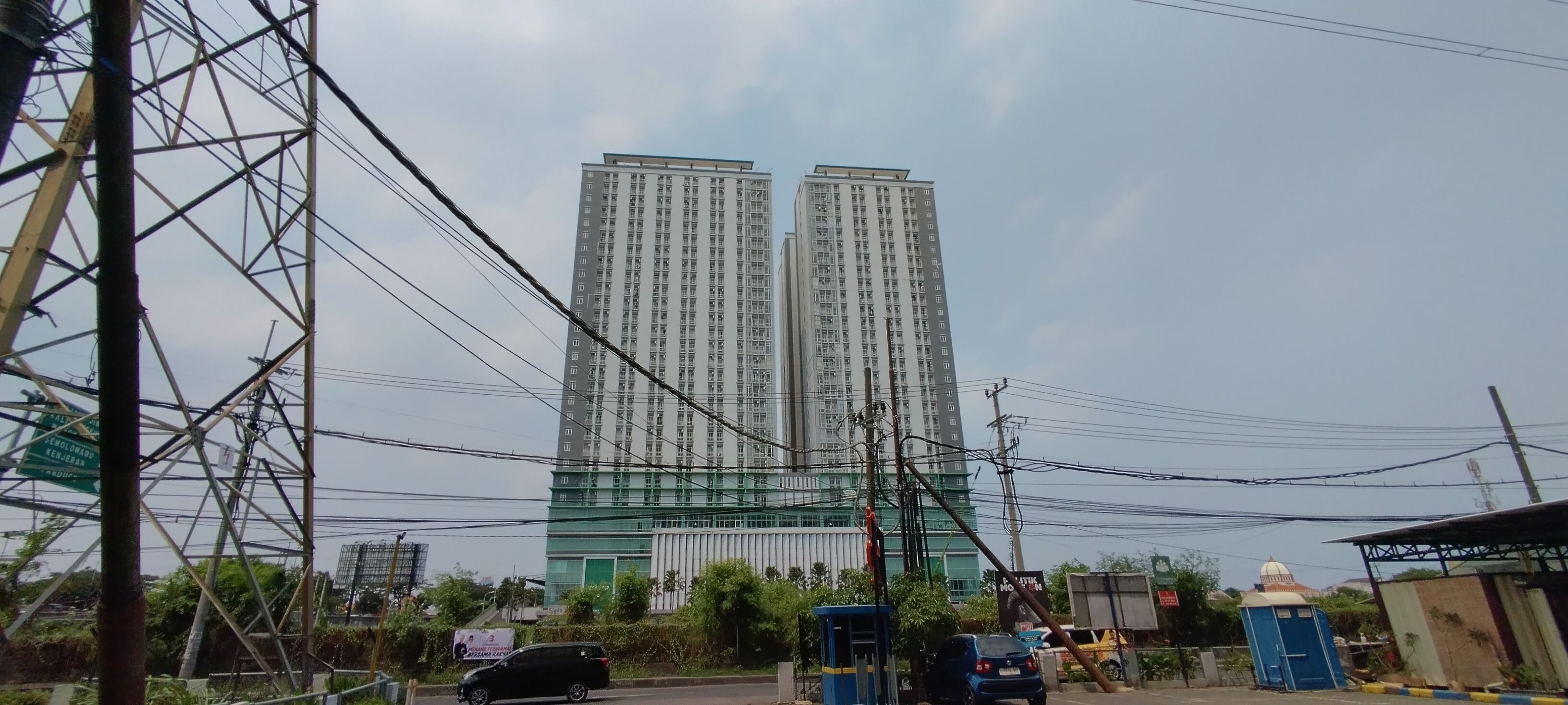 Un grand immeuble d’habitation à plusieurs étages, entouré de lignes électriques et de poteaux de service public.