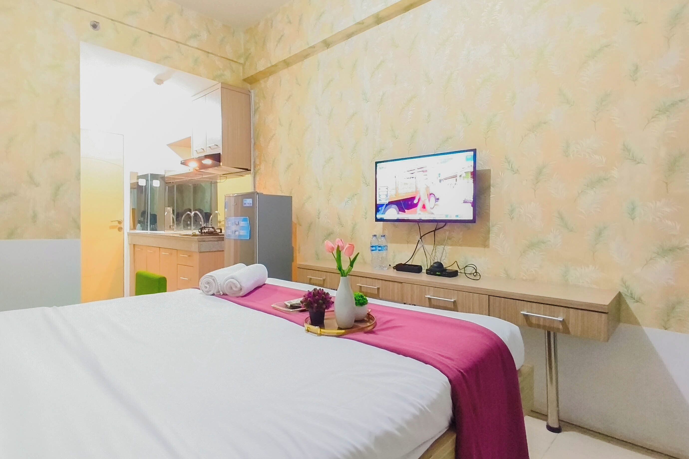 Hotellihuone, jossa on sänky, työpöytä, televisio ja näkyvissä taustalla myös kylpyhuone.