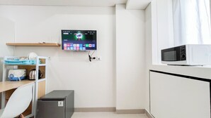 A small kitchenette with a microwave, a refrigerator, and a TV mounted on the wall displaying various apps. - Good Deal Studio (No Kitchen) Bandaraya - Tallasa City Makassar Apartment (Makassar)