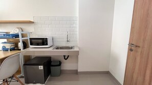 Eine kleine Küchenzeile mit Mikrowelle, Spüle und Stauraumschrank.