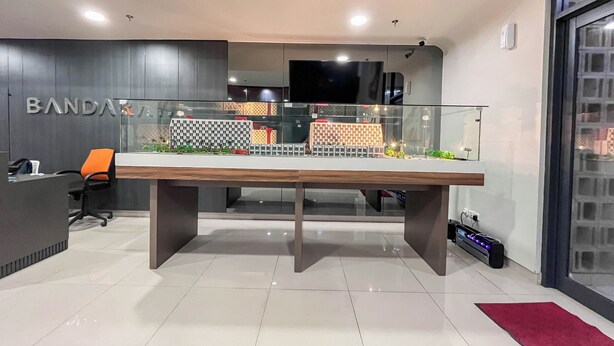 A modern office with a reception desk, a large table with a model cityscape, and a glass partition. - Warm And Comfy Studio Apartment (No Kitchen) Bandaraya - Tallasa City Makassar (Makassar)