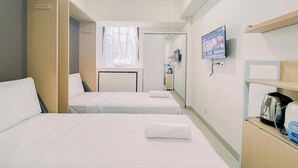 A hotel room with two beds, a TV, a kettle, and a coffee machine. - Warm And Comfy Studio Apartment (No Kitchen) Bandaraya - Tallasa City Makassar (Makassar)