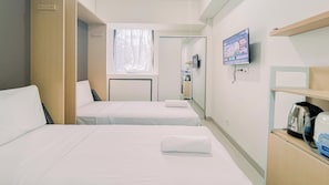 A hotel room with two single beds, a small desk, a television, and a kettle on the sideboard. - Warm And Comfy Studio Apartment (No Kitchen) Bandaraya - Tallasa City Makassar (Makassar)