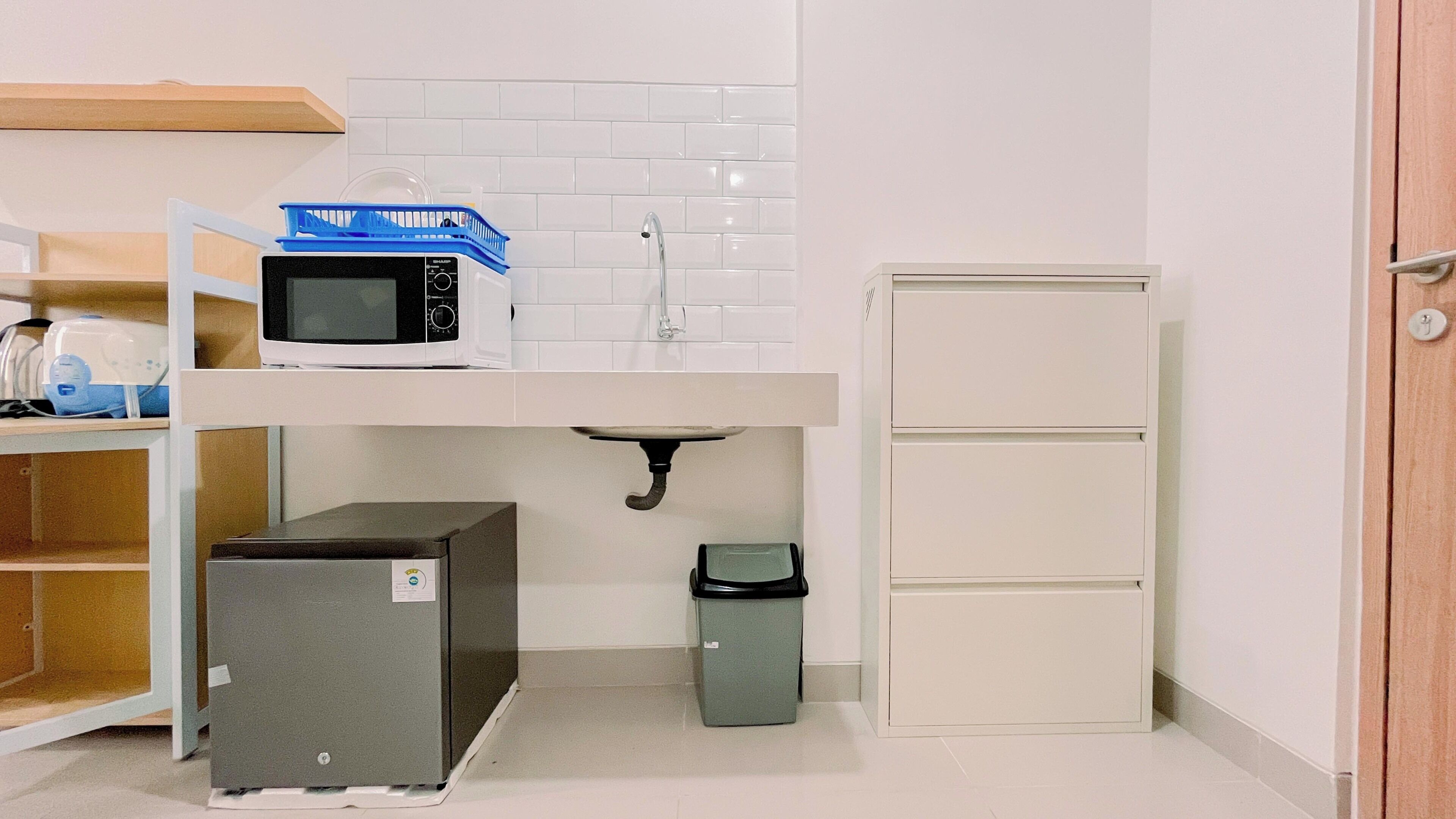 A compact kitchenette with a microwave, sink, and small refrigerator.