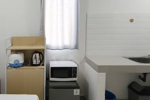 A small kitchenette with a microwave, kettle, and a water dispenser on a shelf. - Best Price Studio (No Kitchen) Apartment At Bandaraya - Tallasa City Makassar (Makassar)