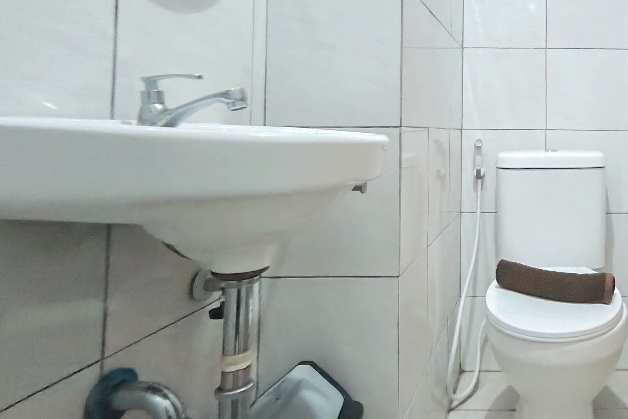 A bathroom with a white sink, a toilet, and a visible pipe.