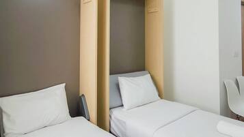 A hotel room with two beds, a chair, and a wooden partition.