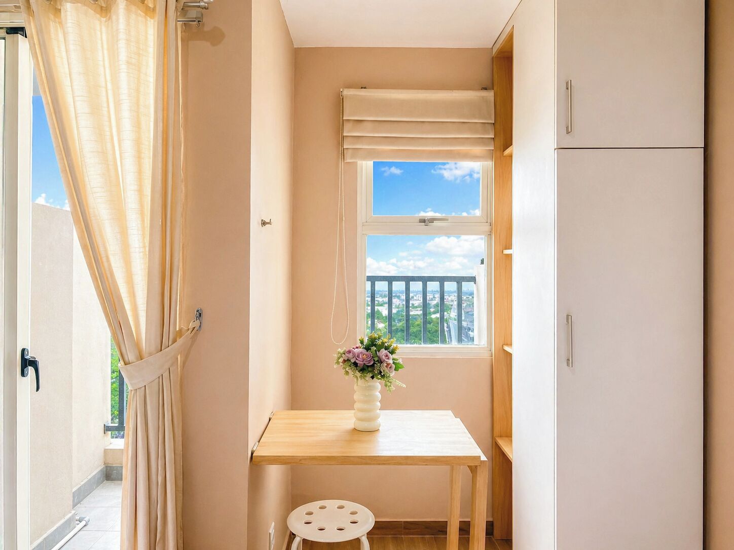 A small room with a window, a table, a stool, and a cabinet.