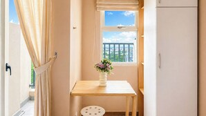 A small room with a window, a table, a stool, and a cabinet. - Homey And Neat Studio Room At Apartment Belmont Residence Puri (Jakarta)