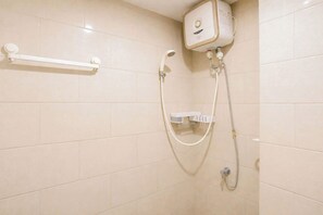 A shower area with a wall-mounted heater, a handheld showerhead, and a control panel. - Tranquil 2Br Direct Access To Mall At Benson Supermall Mansion Apartment (Surabaya)