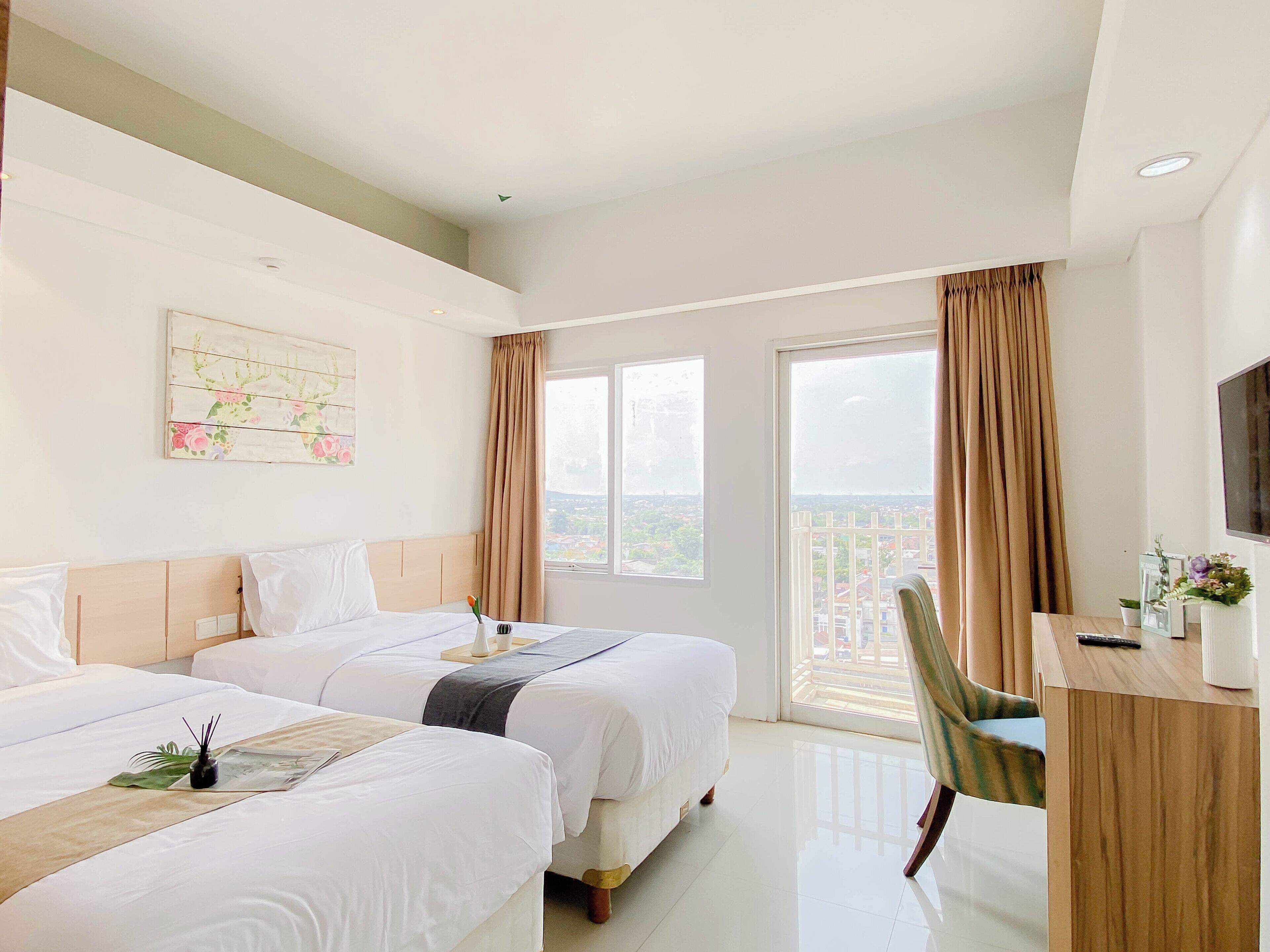 Une chambre d’hôtel avec deux lits, un bureau, une chaise, une télévision et un balcon avec des rideaux.