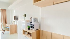 A modern kitchen with a built-in microwave, a coffee maker, and a small plant on the counter. - Comfortable Studio (No Kitchen) At Bogor Icon Apartment (Bogor)