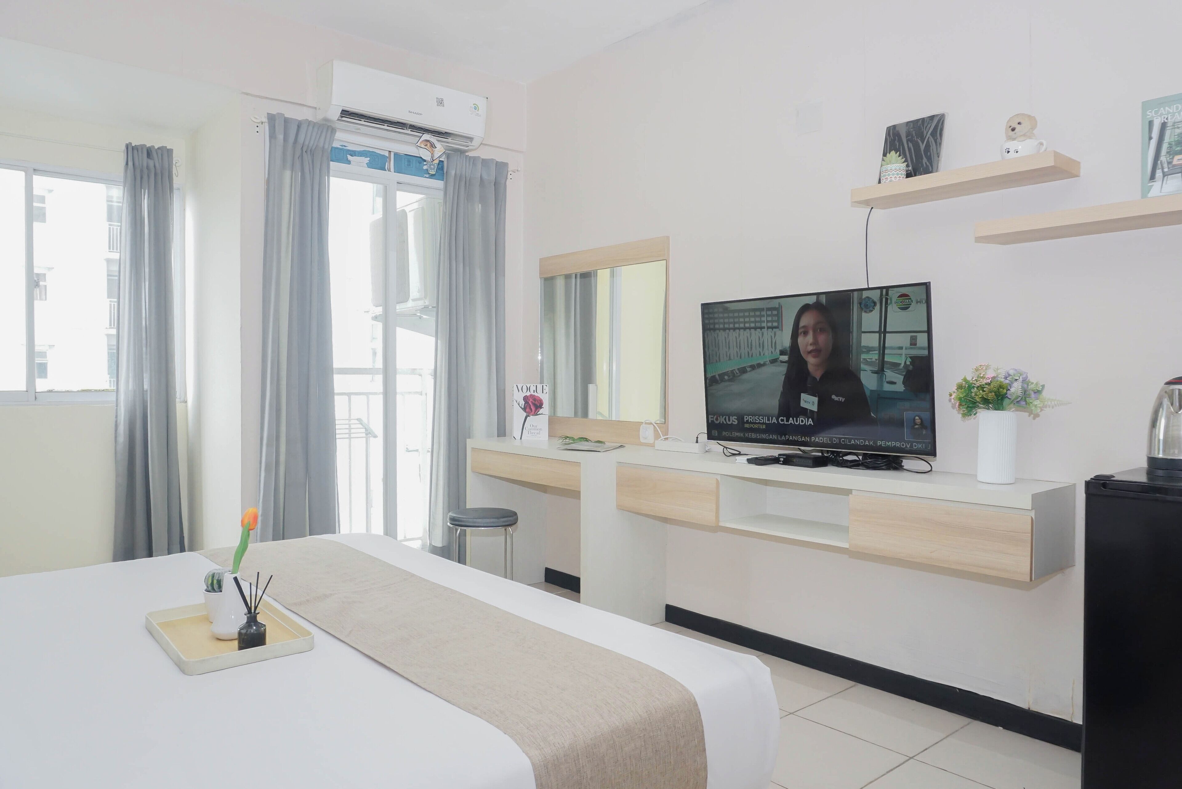 A hotel room with a bed, a desk, a television, and a window with curtains.