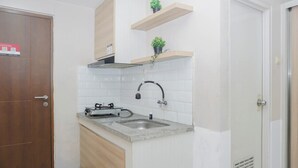 Uma cozinha com pia dupla, armários de madeira, azulejos brancos e uma pequena planta em uma prateleira.