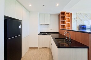 Eine moderne Küche mit einem schwarzen Kühlschrank, weißen Schränken, einem Holzbodenregal und einer Marmor-Spritzschutzwand.