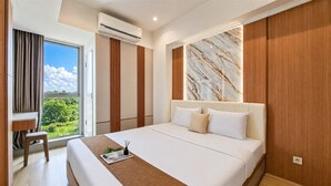 Quarto de hotel moderno com uma cama grande, uma escrivaninha e vista para o verde.