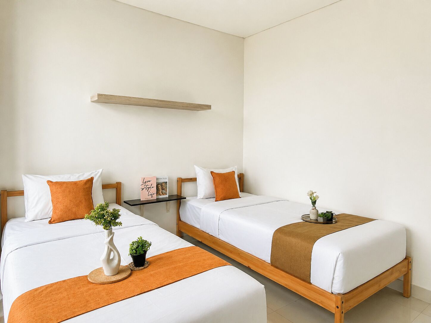 Une chambre d’hôtel avec deux lits, une petite table, une étagère et une plante en pot.