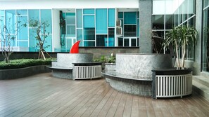 Ein moderner Außenbereich mit Rundplanzengefäßen, einer roten Skulptur und einem Gebäude mit großen Fenstern im Hintergrund.