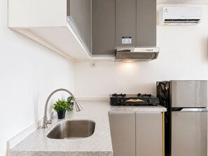 Eine Küche mit Edelstahlspüle, Gasherd, Backofen und Kühlschrank.
