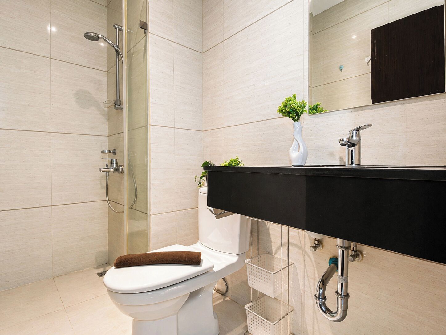 A modern bathroom with a shower, toilet, sink, and a mirror.