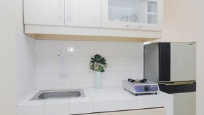 Una cocina con armarios blancos, un fregadero, un florero con flores y una estufa a gas.