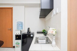 Eine kleine Küche mit Wasserspender, Wasserkocher, Spüle und einem Blumentopf.