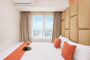 Ett hotellrum med en säng, gardiner, ett fönster med utsikt över staden och en luftkonditioneringsanläggning.