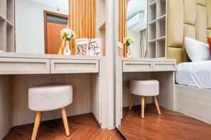 Ein Schlafzimmer mit einem Bett, einem Schreibtisch mit Stuhl, einem Kleiderschrank und einem Spiegel.