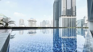 Una piscina en la azotea con vistas a un paisaje urbano, rodeada de edificios altos.