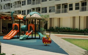 A playground with slides and a small red toy train. - 1 Pax Wooden Touch Studio At Citra Living Apartment (Jakarta)