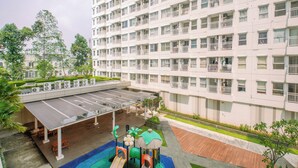 A multi-story residential building with balconies, a covered parking area, and a playground. - Homey And Neat Studio Room At Apartment Citra Living (Jakarta)