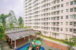 Ein mehrstöckiges Wohnhaus mit Balkonen, überdachten Parkplätzen und einem Spielplatz.